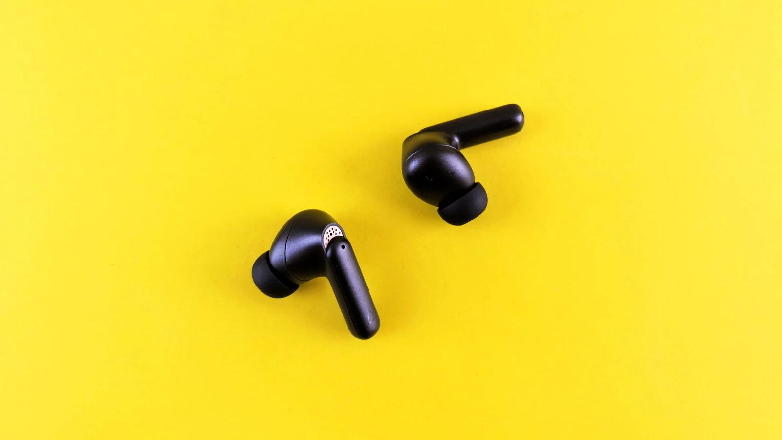دو ایرباد بی‌سیم مشکی معمولی روی زمینه زرد؛ تصویر توضیحی و نه محصولات Bose